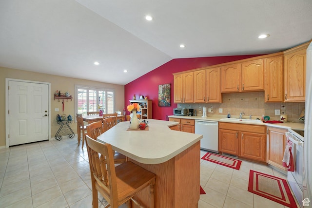 kitchen featuring white appliances, a sink, vaulted ceiling, light countertops, and a center island