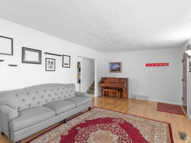 living area featuring wood finished floors, baseboards, and a textured ceiling