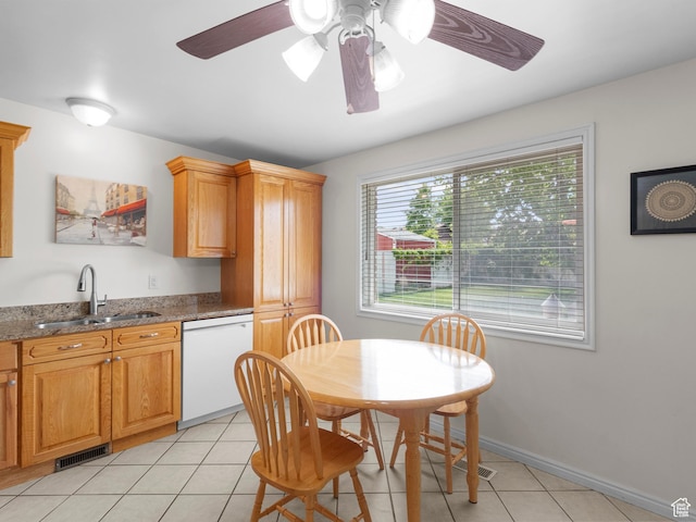 kitchen with dishwasher, a sink, light tile patterned floors, ceiling fan, and stone countertops