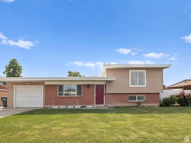 split level home featuring an attached garage, a front lawn, brick siding, and driveway
