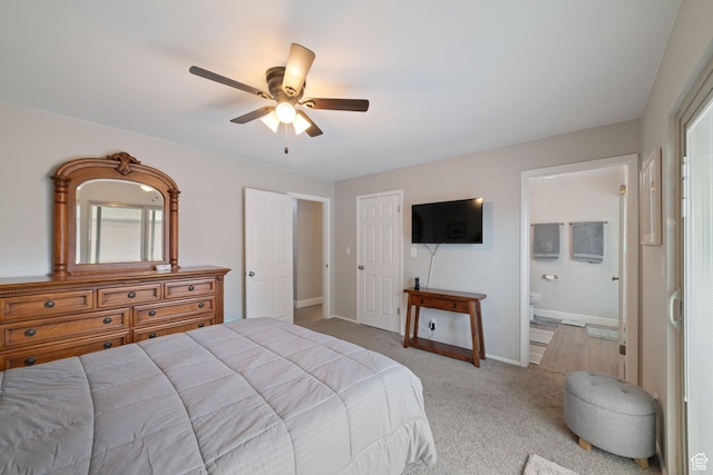 bedroom featuring light colored carpet, baseboards, connected bathroom, a ceiling fan, and a closet