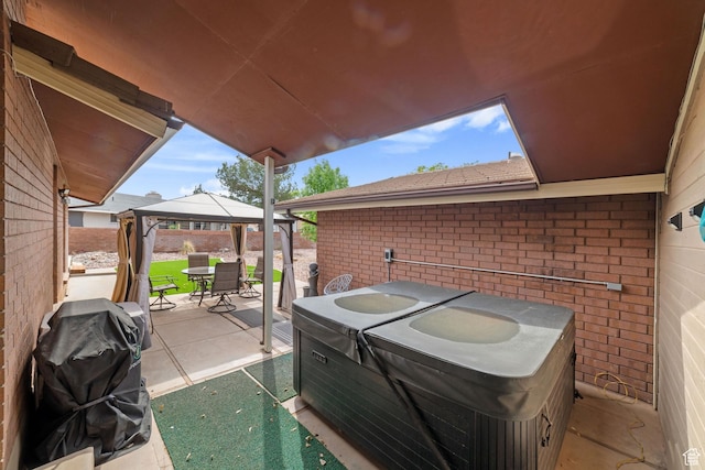 view of patio / terrace featuring a gazebo, a hot tub, and outdoor dining space