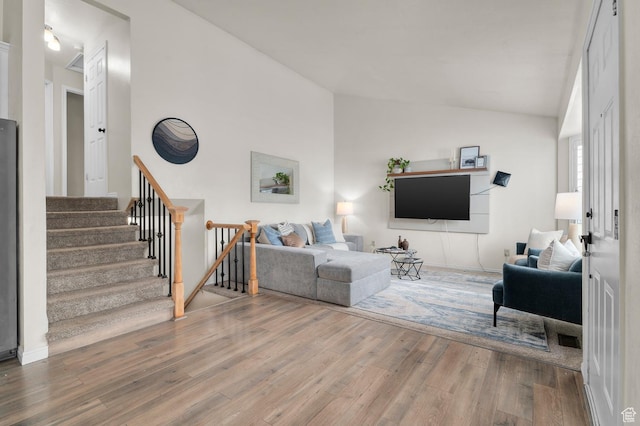 living room with lofted ceiling, wood finished floors, and stairway