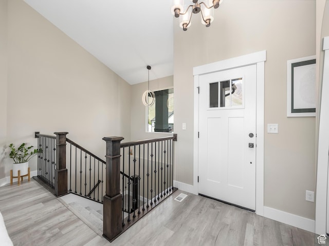 foyer with wood finished floors, a chandelier, and baseboards
