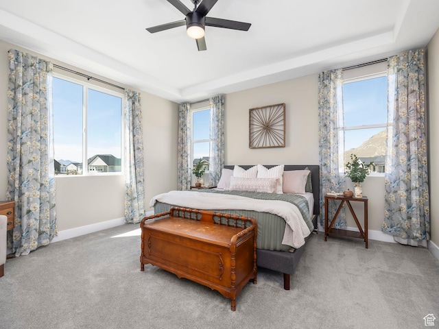 bedroom featuring baseboards, carpet floors, a tray ceiling, and a ceiling fan