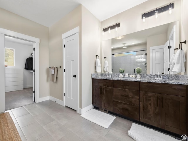 bathroom featuring double vanity, healthy amount of natural light, a shower stall, and baseboards