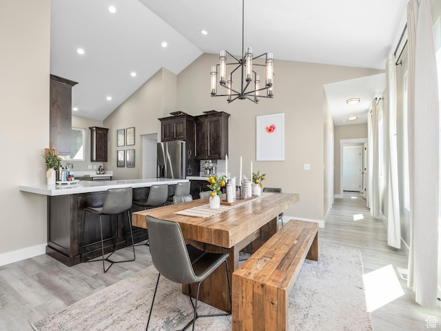 dining area with high vaulted ceiling, light wood finished floors, a chandelier, baseboards, and recessed lighting