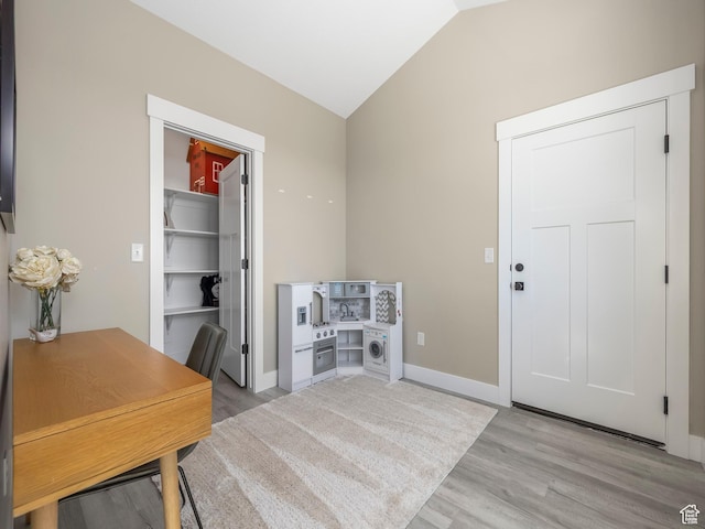home office featuring light wood-style floors, vaulted ceiling, and baseboards