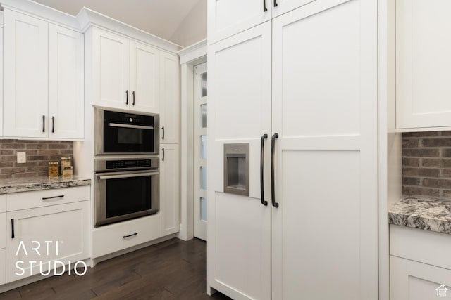 kitchen with paneled fridge, dark wood finished floors, backsplash, white cabinets, and light stone countertops