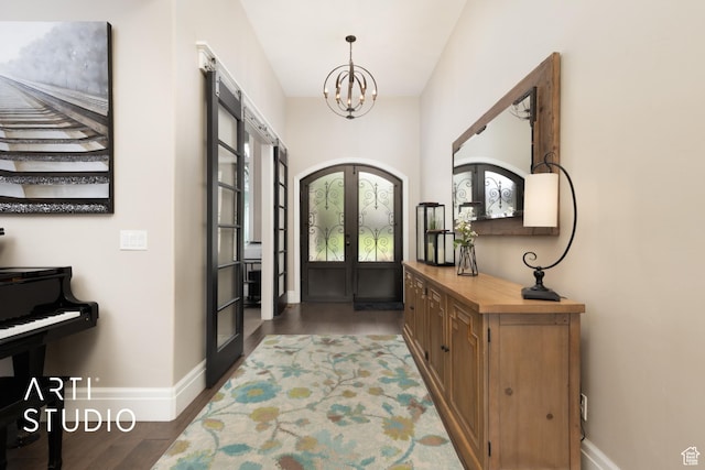 foyer entrance featuring french doors, baseboards, a chandelier, and wood finished floors