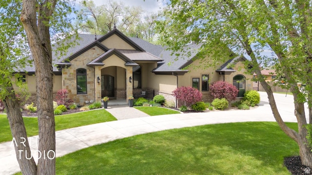 view of front of home featuring stone siding, stucco siding, a front lawn, and driveway