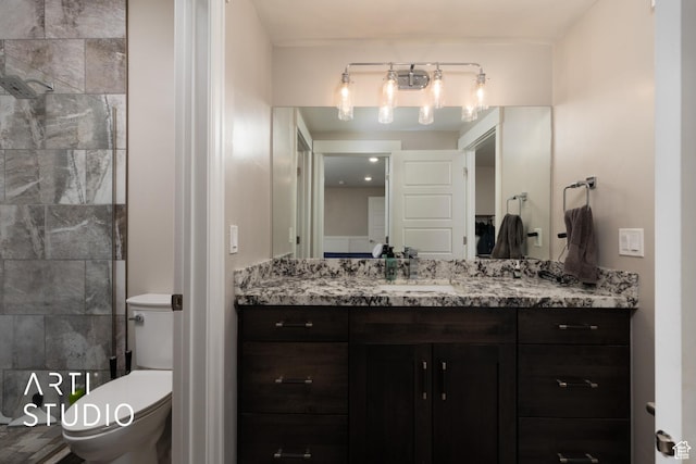 bathroom with toilet, vanity, and tiled shower