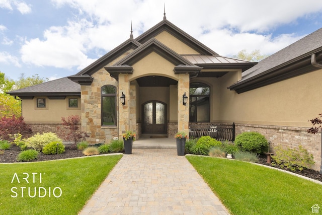 property entrance with stucco siding, a yard, french doors, and a standing seam roof