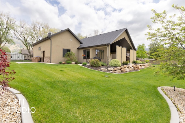 back of house with a lawn and stucco siding