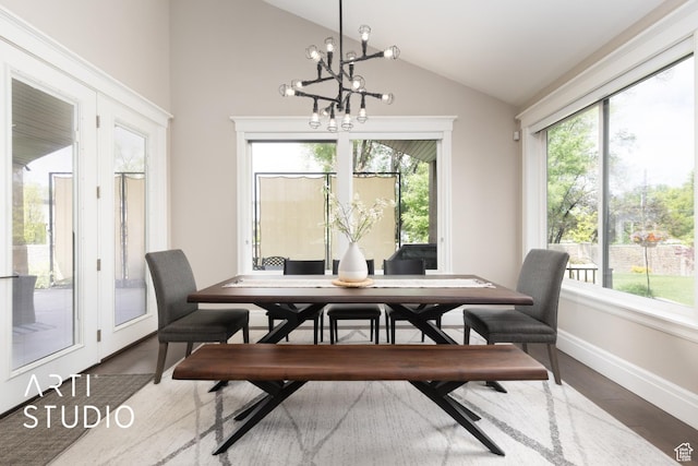 dining room featuring lofted ceiling, healthy amount of natural light, a chandelier, wood finished floors, and baseboards