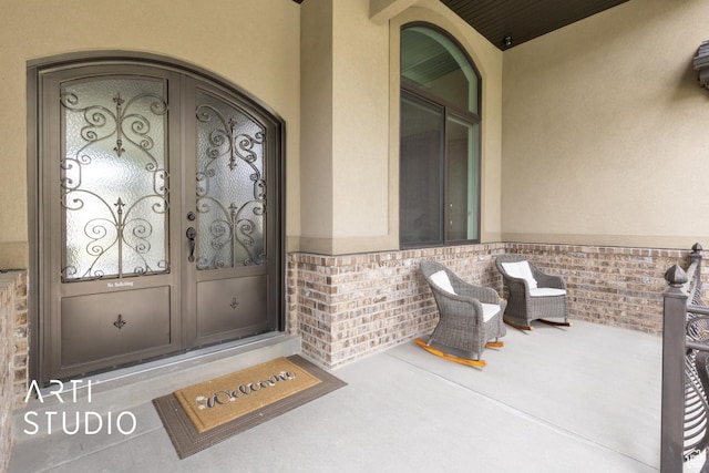 view of exterior entry featuring stucco siding and brick siding