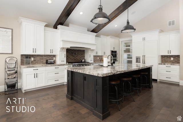 kitchen featuring backsplash, a kitchen breakfast bar, a sink, white cabinets, and recessed lighting