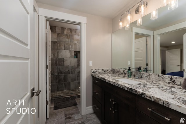 full bathroom with vanity, a tile shower, and toilet