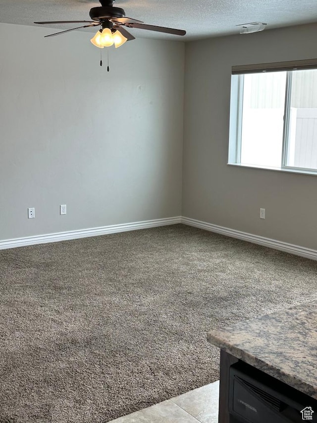 carpeted empty room with a ceiling fan, a textured ceiling, and baseboards