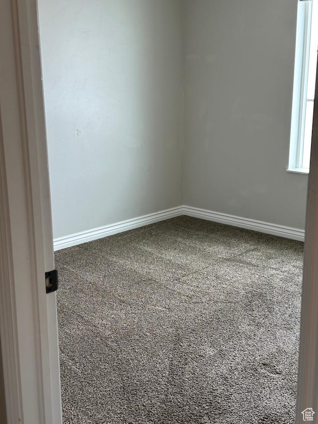 carpeted empty room featuring baseboards
