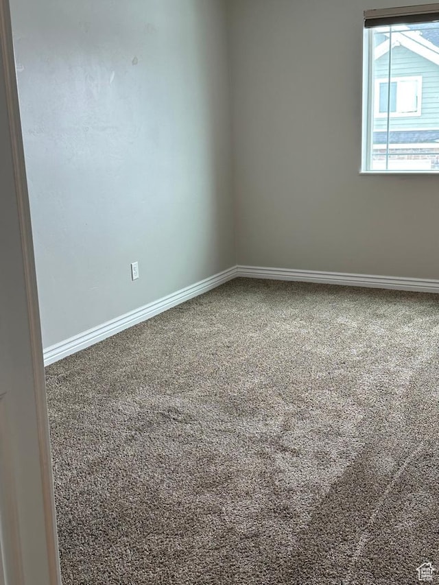 carpeted empty room featuring baseboards