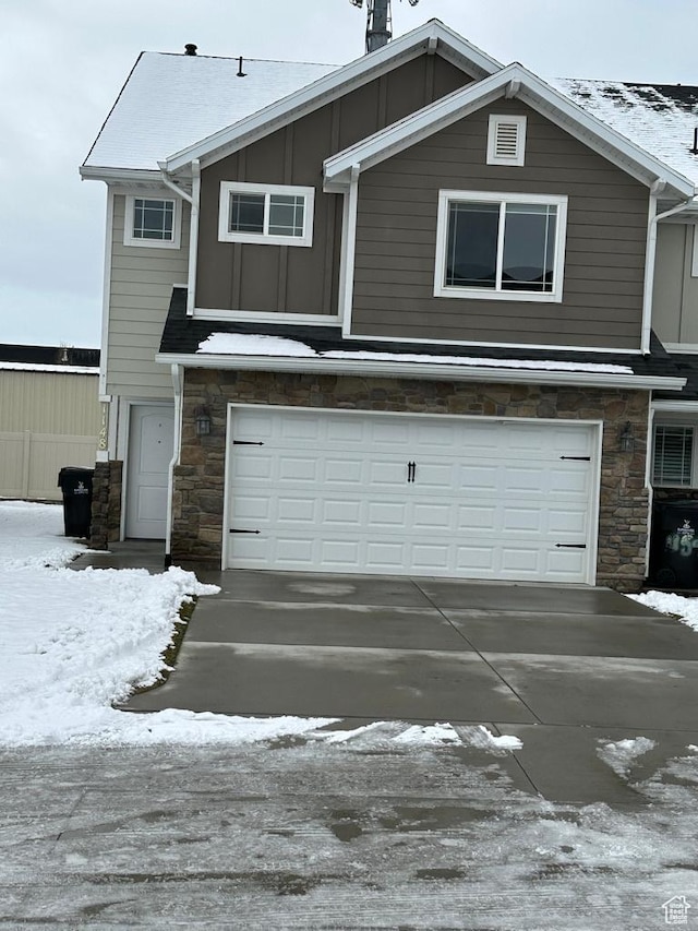 view of front of property featuring stone siding, an attached garage, concrete driveway, and board and batten siding