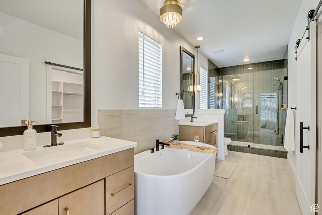 bathroom featuring a shower stall, a freestanding tub, toilet, two vanities, and tile patterned floors