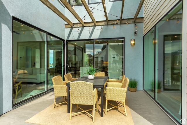 sunroom featuring wood finished floors, a skylight, a high ceiling, and outdoor dining area