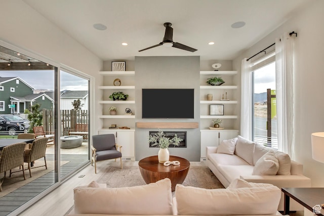 living room featuring light wood finished floors, healthy amount of natural light, ceiling fan, built in features, and recessed lighting