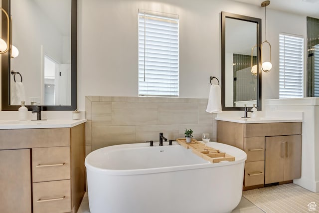 full bath with healthy amount of natural light, a soaking tub, two vanities, and tile patterned flooring