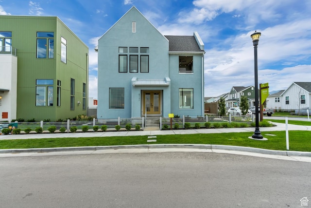 view of front facade featuring french doors, a fenced front yard, stucco siding, and a residential view