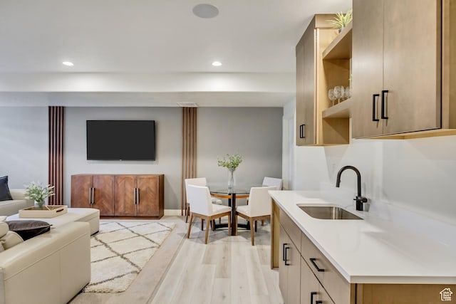 kitchen with a sink, open floor plan, light wood finished floors, light countertops, and recessed lighting