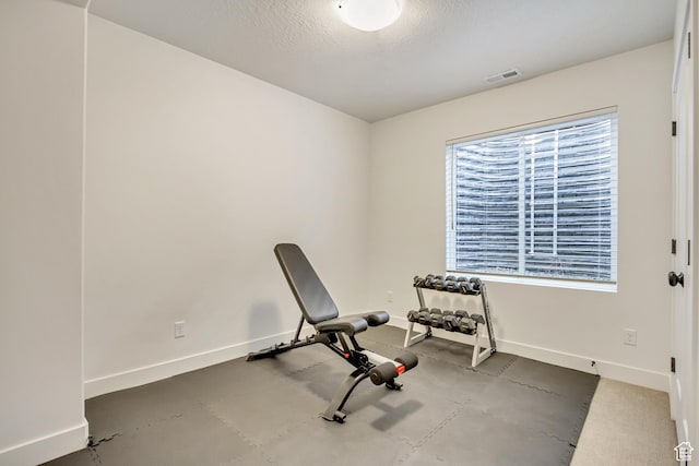 exercise area with baseboards and a textured ceiling