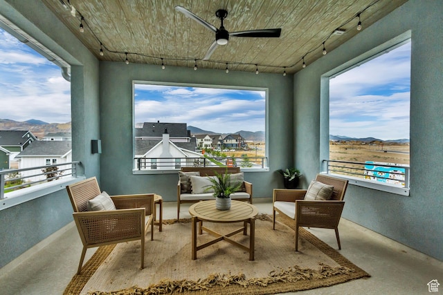 sitting room featuring rail lighting, a mountain view, ceiling fan, and plenty of natural light