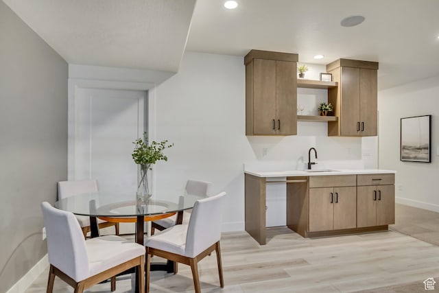 kitchen featuring open shelves, a sink, baseboards, light wood finished floors, and light countertops