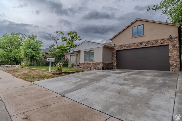 view of front of house featuring stone siding, stucco siding, concrete driveway, and a garage