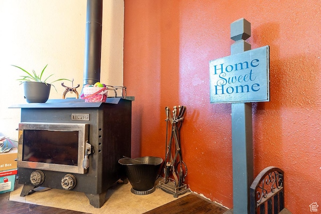 detailed view of wood finished floors, a wood stove, and a textured wall