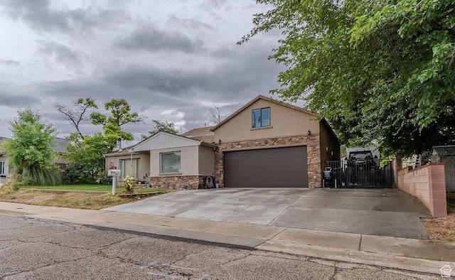 view of front of house with stone siding, stucco siding, driveway, and fence