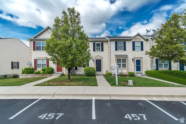 view of property with uncovered parking, a front yard, entry steps, and stucco siding