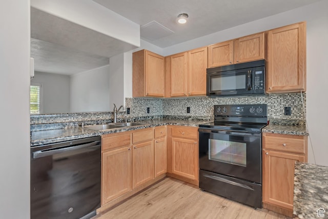 kitchen featuring black appliances, a sink, light wood finished floors, and light brown cabinets