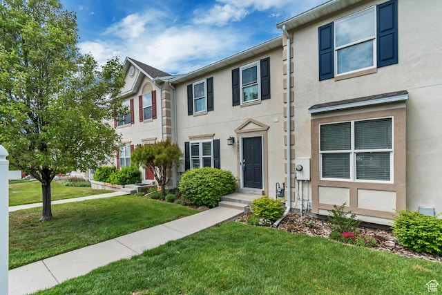 townhome / multi-family property with stucco siding and a front yard