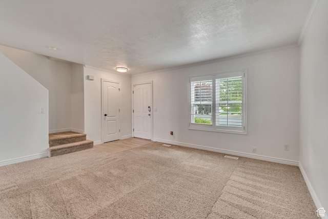 spare room with light carpet, baseboards, stairs, and crown molding