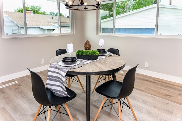 dining room with a chandelier, plenty of natural light, baseboards, and wood finished floors