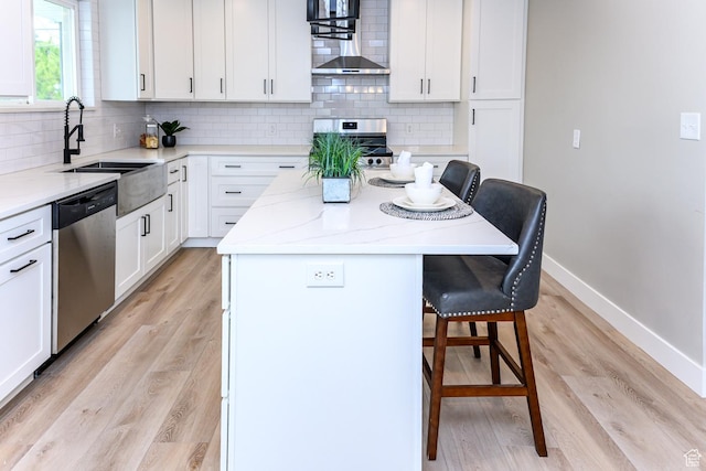 kitchen with appliances with stainless steel finishes, a sink, a breakfast bar, a kitchen island, and baseboards