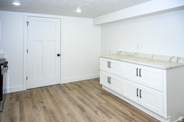 bar area with a textured ceiling, light wood-type flooring, baseboards, and recessed lighting