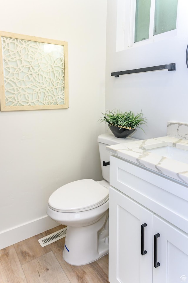 bathroom featuring wood finished floors, toilet, vanity, and baseboards