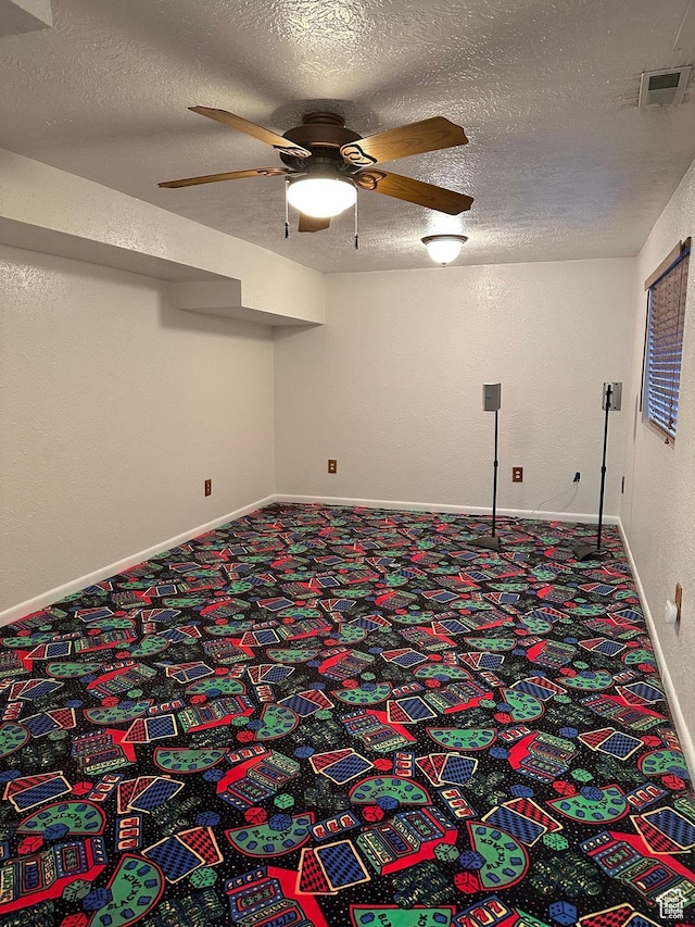 carpeted empty room with ceiling fan and a textured ceiling