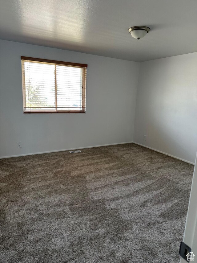 unfurnished room with carpet flooring and baseboards