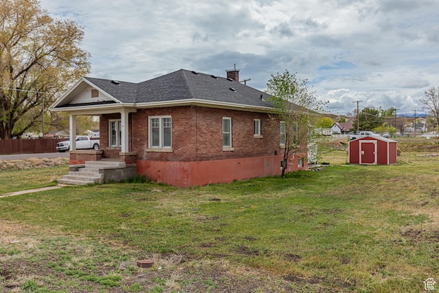 98 S Center St, Redmond, UT 84652 - view of side of property with a storage unit, brick siding, roof with shingles, and a lawn