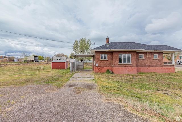 98 S Center St, Redmond, UT 84652 - view of side of home with driveway, a storage shed, brick siding, a chimney, and an outdoor structure